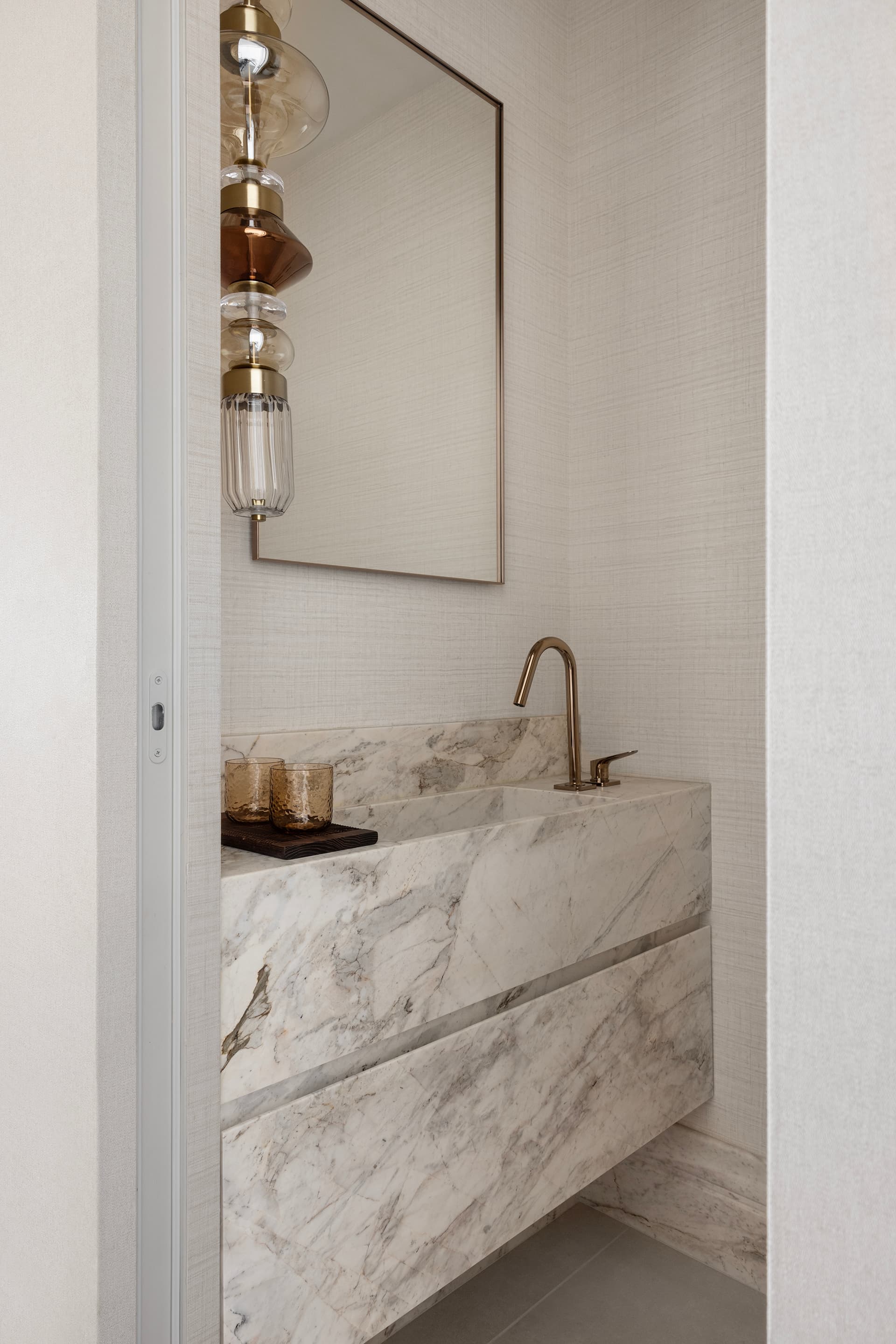 Powder room with monolithic marble vanity and glass pendant