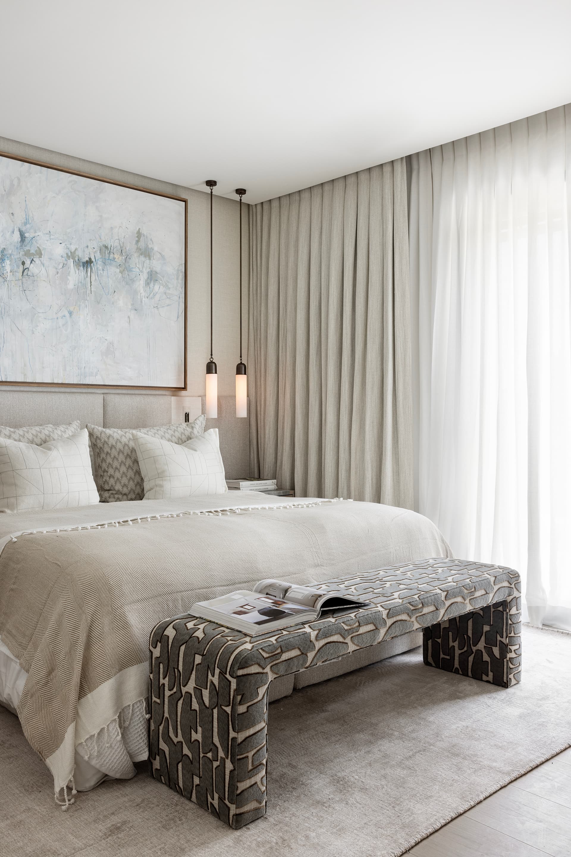 Master bedroom with bench and floor-length drapes