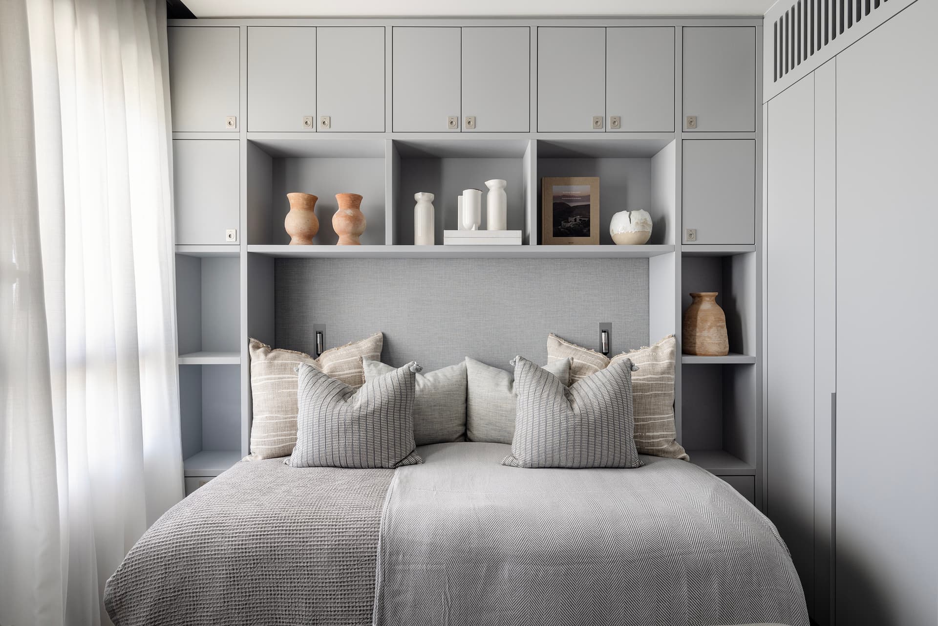 Secondary bedroom with grey built-in headboard wall and terracotta ceramics