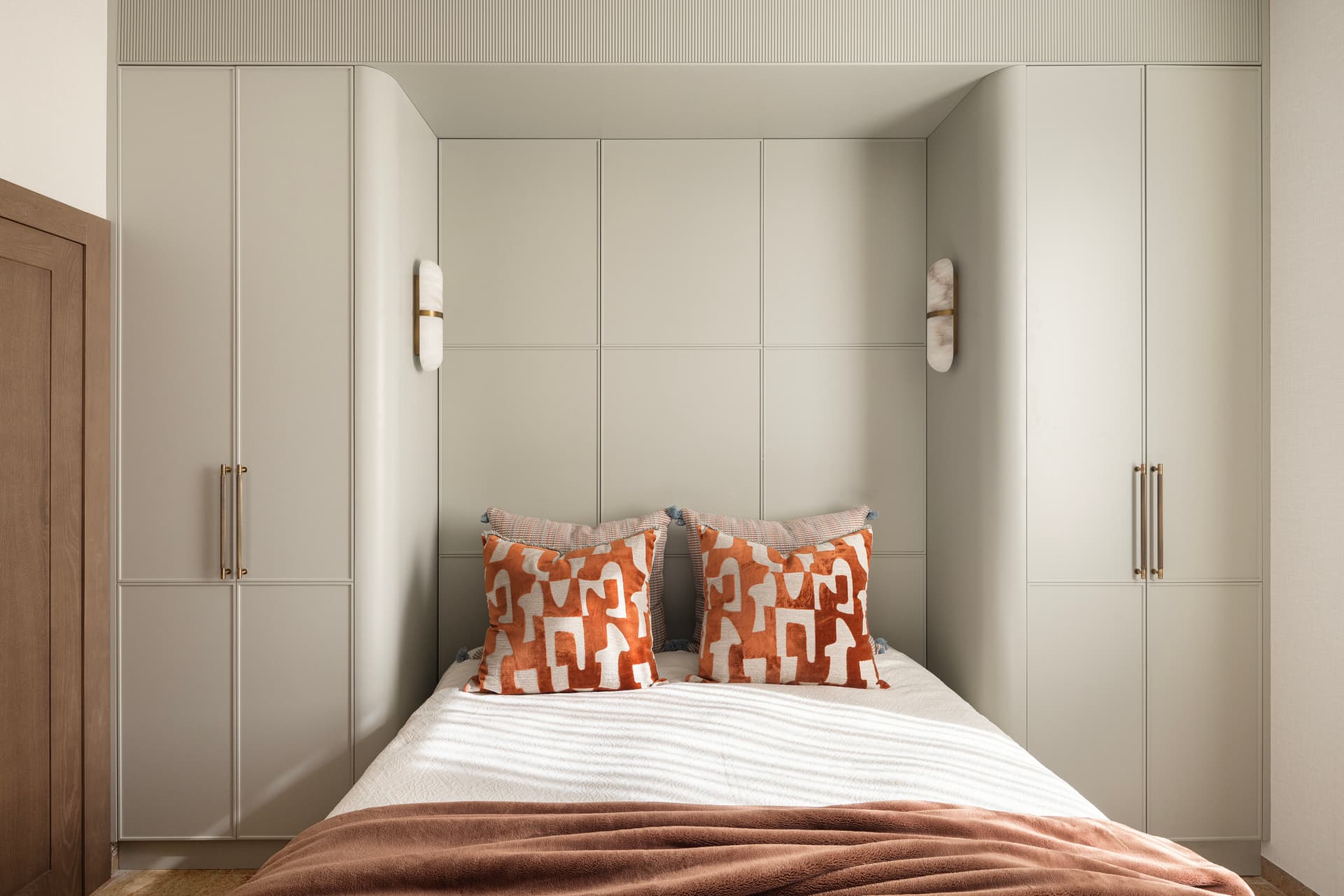 Bedroom with bespoke sage green fitted wardrobes and brass hardware